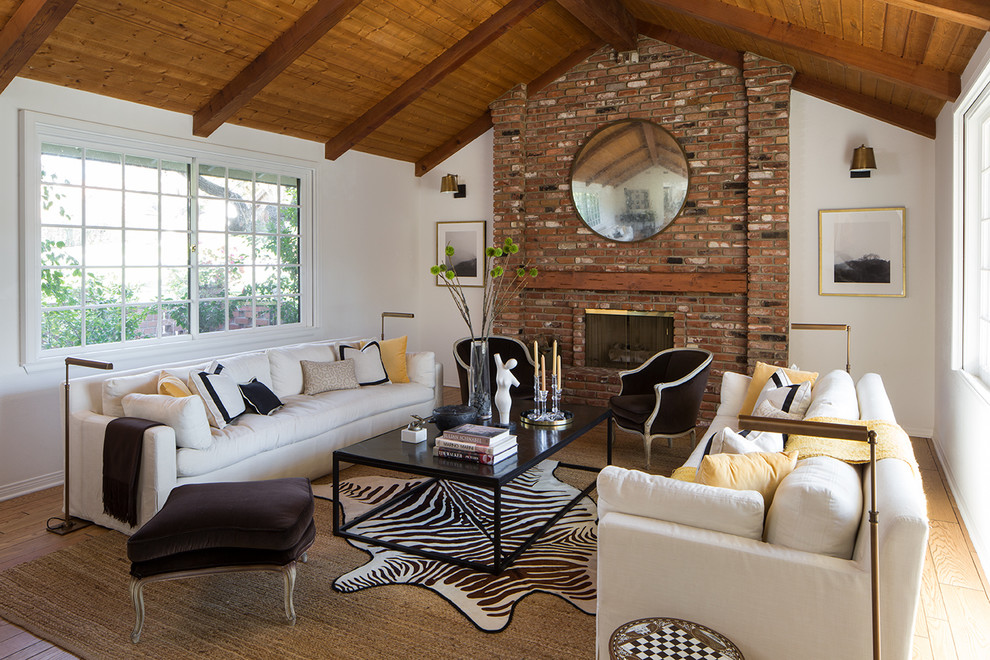Photo of a medium sized traditional formal open plan living room in Los Angeles with white walls, light hardwood flooring, a standard fireplace, a brick fireplace surround, no tv and brown floors.