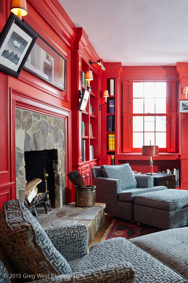 Exemple d'un grand salon éclectique ouvert avec une salle de réception, un mur rouge, un sol en bois brun, une cheminée standard, un manteau de cheminée en pierre, aucun téléviseur et un sol marron.