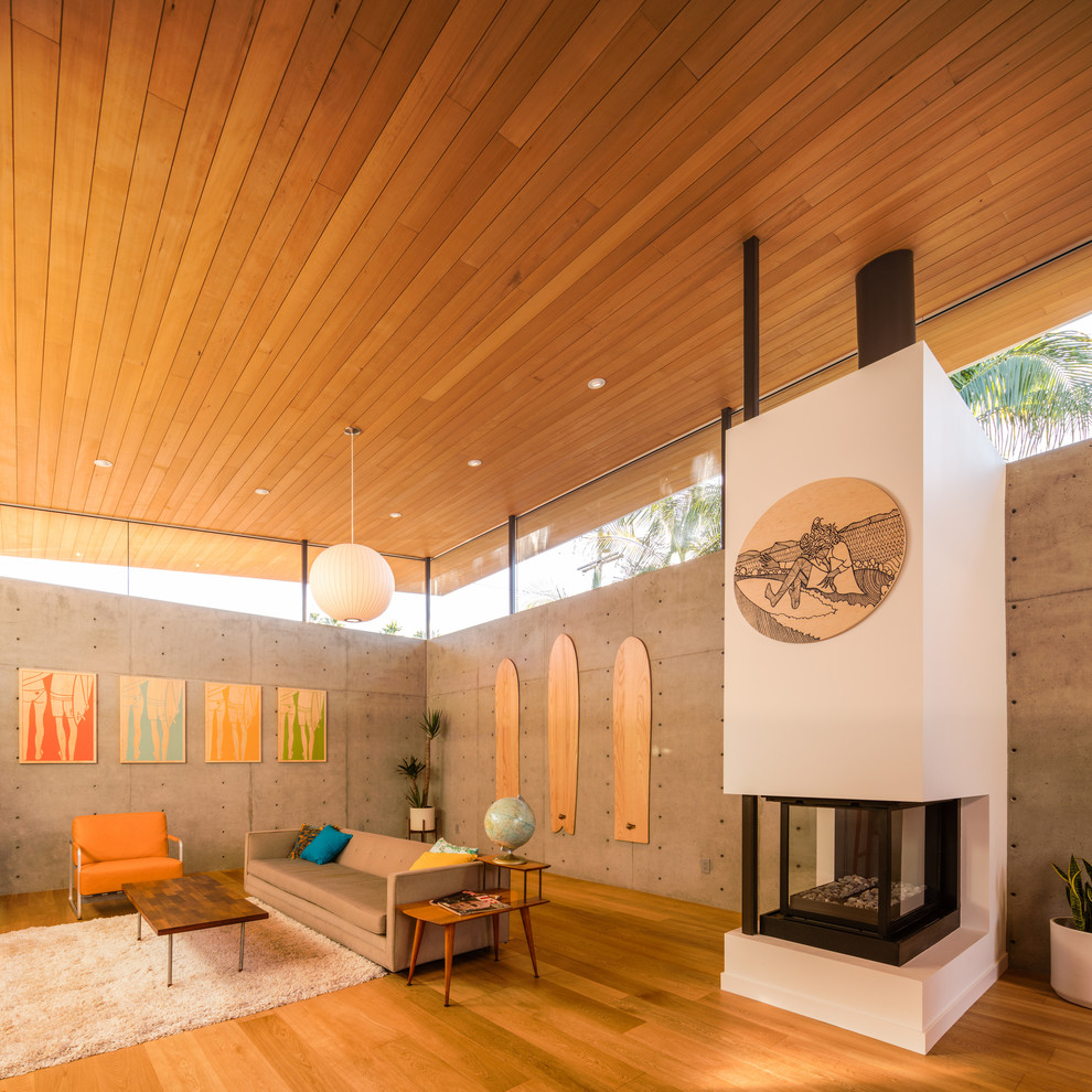 Offenes Retro Wohnzimmer mit weißer Wandfarbe, braunem Holzboden, Tunnelkamin und verputzter Kaminumrandung in San Diego