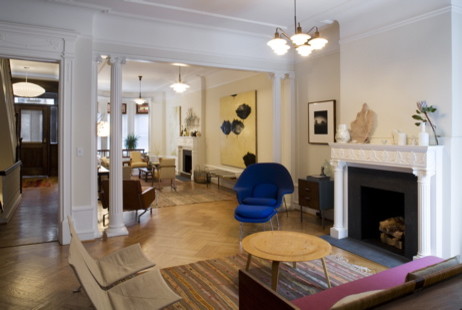 Exemple d'un petit salon éclectique ouvert avec un mur blanc, parquet clair, une cheminée standard, un manteau de cheminée en plâtre, aucun téléviseur et un sol beige.