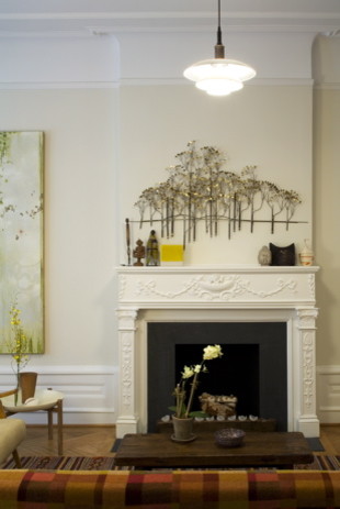 Cette image montre un petit salon bohème ouvert avec un mur blanc, parquet clair, une cheminée standard, un manteau de cheminée en plâtre, aucun téléviseur et un sol beige.