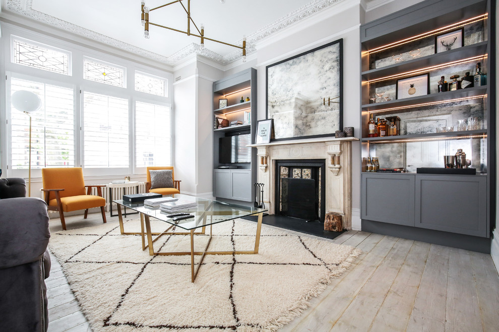 Mittelgroßes, Abgetrenntes Modernes Wohnzimmer mit grauer Wandfarbe, hellem Holzboden, Kamin, Kaminumrandung aus Stein, freistehendem TV und grauem Boden in London
