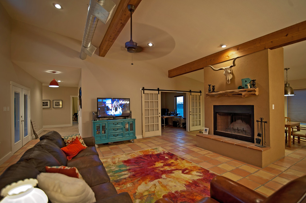 オースティンにある中くらいなサンタフェスタイルのおしゃれなLDK (ベージュの壁、テラコッタタイルの床、標準型暖炉、据え置き型テレビ) の写真