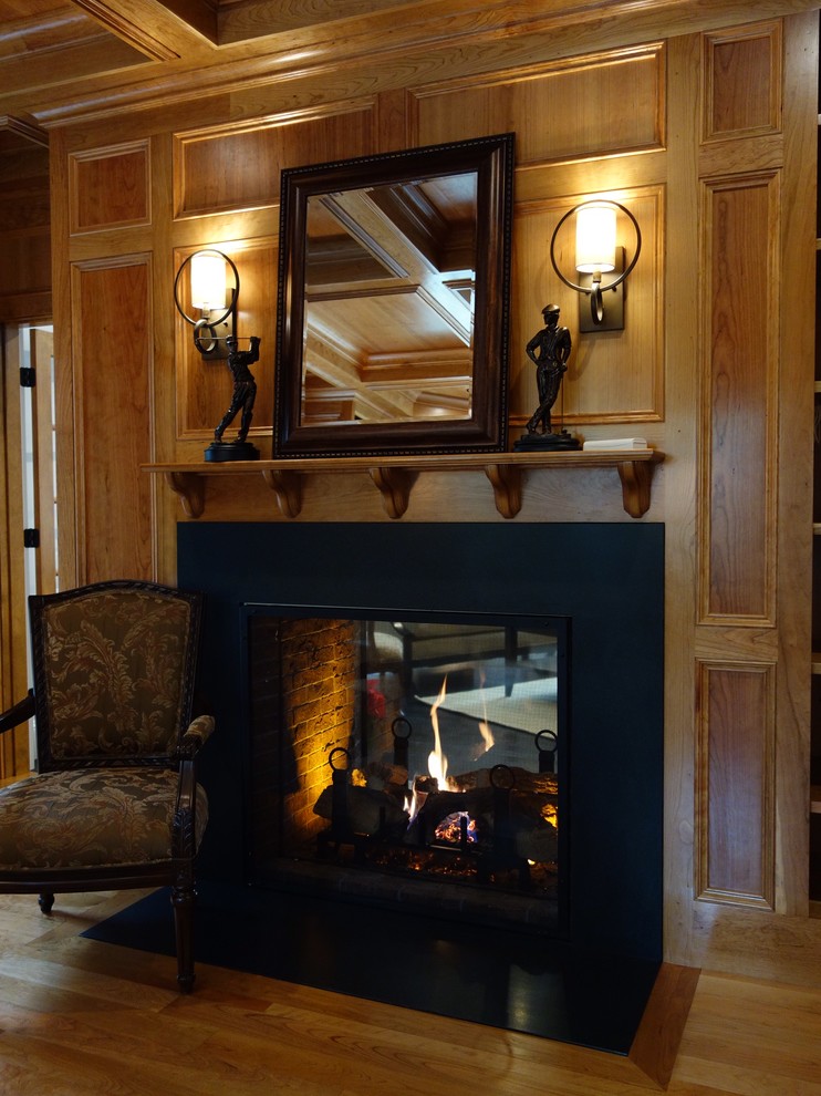 ボストンにあるラグジュアリーな中くらいなトラディショナルスタイルのおしゃれな独立型リビング (茶色い壁、無垢フローリング、標準型暖炉、木材の暖炉まわり) の写真