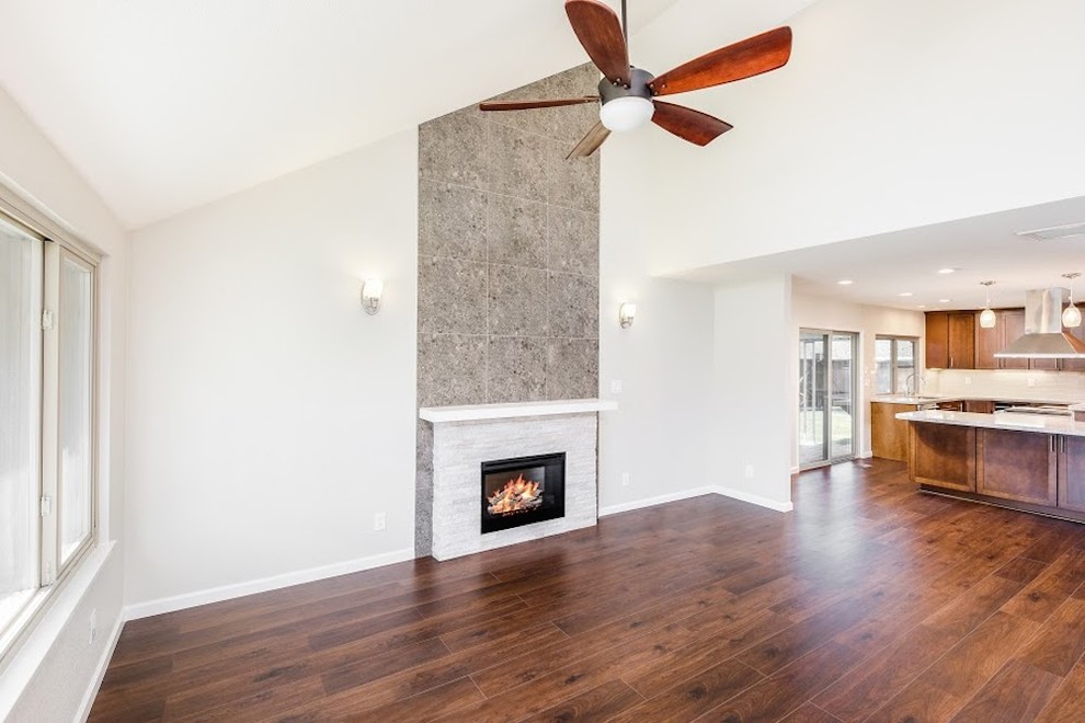 This is an example of a medium sized contemporary open plan living room in Sacramento with white walls, dark hardwood flooring, a standard fireplace and a stone fireplace surround.