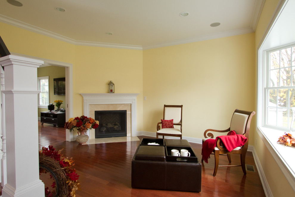 Идея дизайна: парадная, изолированная гостиная комната среднего размера в стиле неоклассика (современная классика) с желтыми стенами, паркетным полом среднего тона, угловым камином и фасадом камина из камня без телевизора
