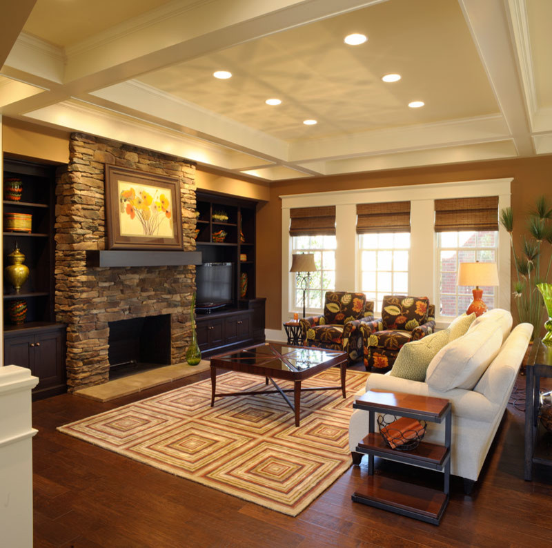 Стильный дизайн: парадная, открытая гостиная комната в классическом стиле с коричневыми стенами, стандартным камином, фасадом камина из каменной кладки, мультимедийным центром и кессонным потолком - последний тренд