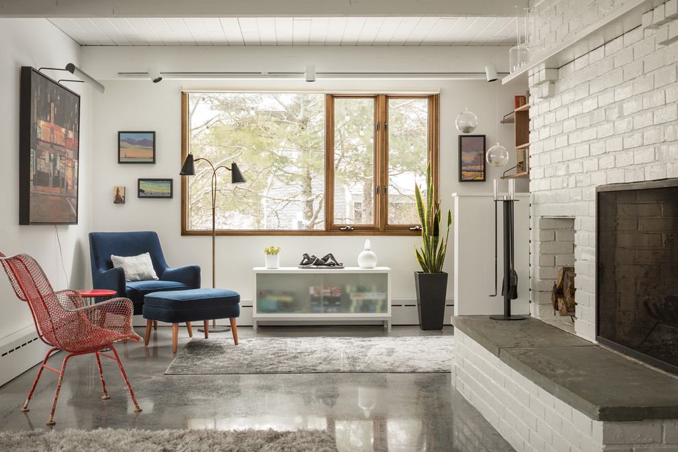 Стильный дизайн: изолированная гостиная комната в стиле ретро с белыми стенами, бетонным полом, стандартным камином и фасадом камина из кирпича без телевизора - последний тренд