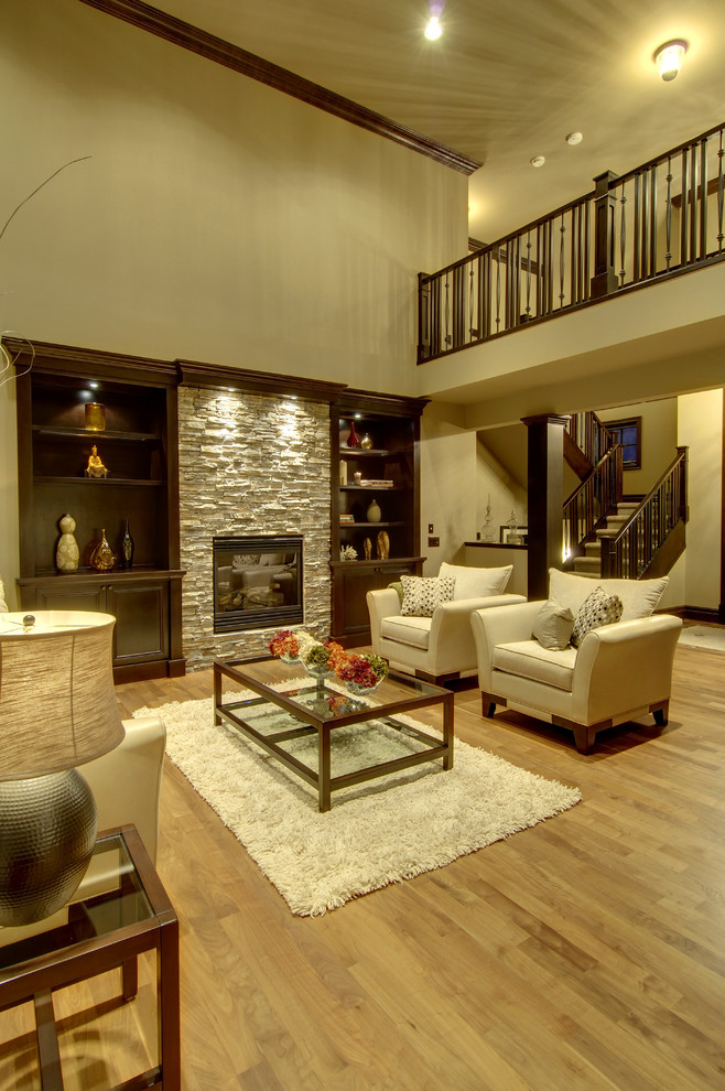 Ejemplo de salón abierto clásico renovado grande con paredes beige, suelo de madera en tonos medios, todas las chimeneas y marco de chimenea de piedra
