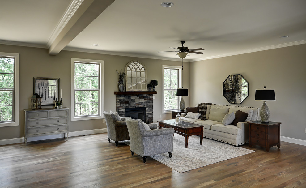 Ejemplo de salón abierto de estilo americano de tamaño medio con paredes grises, suelo de madera en tonos medios, todas las chimeneas y marco de chimenea de piedra