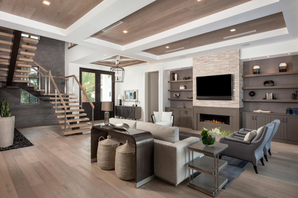 Cette image montre un salon design ouvert avec un mur blanc, un sol en bois brun, une cheminée ribbon, un téléviseur fixé au mur, un sol marron et un plafond décaissé.