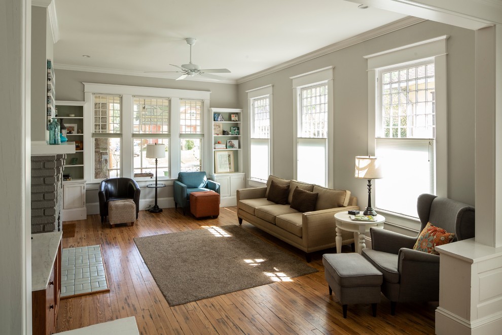Diseño de salón de estilo americano con paredes grises, suelo de madera en tonos medios y suelo marrón