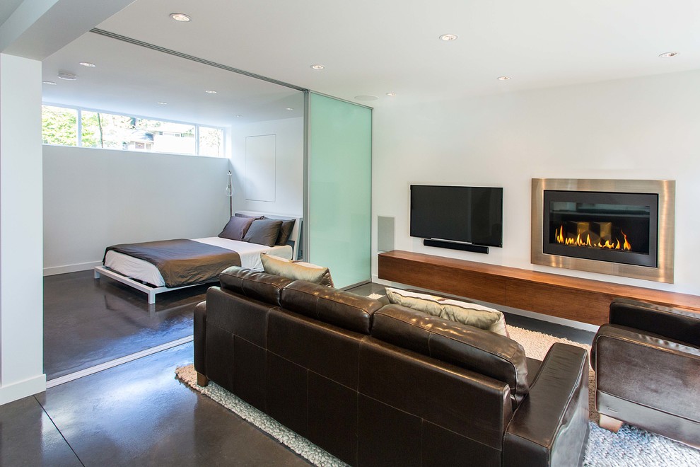 Offenes Modernes Wohnzimmer mit weißer Wandfarbe, Betonboden, Gaskamin, Kaminumrandung aus Metall und TV-Wand in Vancouver