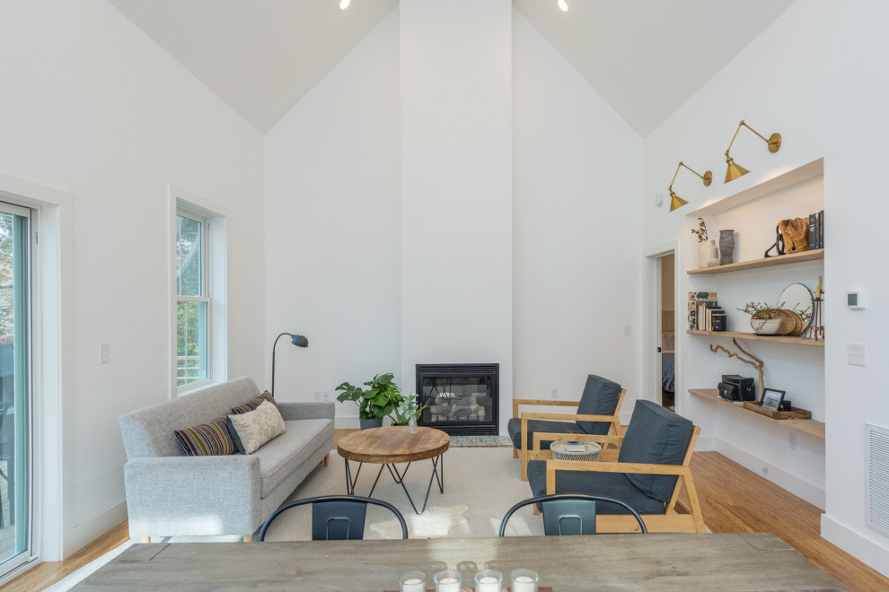 他の地域にある低価格の小さなトランジショナルスタイルのおしゃれなLDK (白い壁、標準型暖炉、茶色い床、竹フローリング) の写真