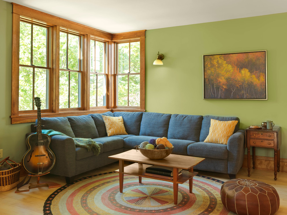 Mittelgroßes Wohnzimmer mit grüner Wandfarbe, hellem Holzboden, Kaminumrandung aus Stein und Kaminofen in Burlington