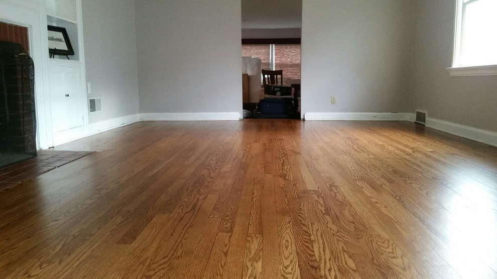 Mittelgroßes Klassisches Wohnzimmer mit grauer Wandfarbe, braunem Holzboden, Kamin, Kaminumrandung aus Backstein und braunem Boden in St. Louis
