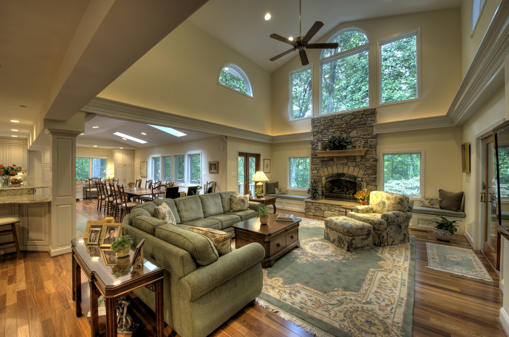 На фото: гостиная комната в классическом стиле с фасадом камина из камня и ковром на полу с
