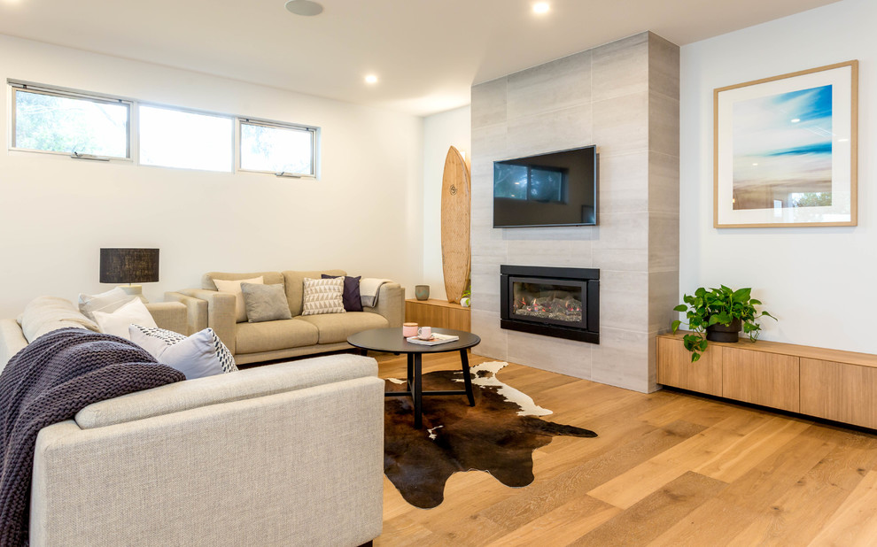 Abgetrenntes Modernes Wohnzimmer mit weißer Wandfarbe, hellem Holzboden, Gaskamin, gefliester Kaminumrandung, TV-Wand und beigem Boden in Adelaide