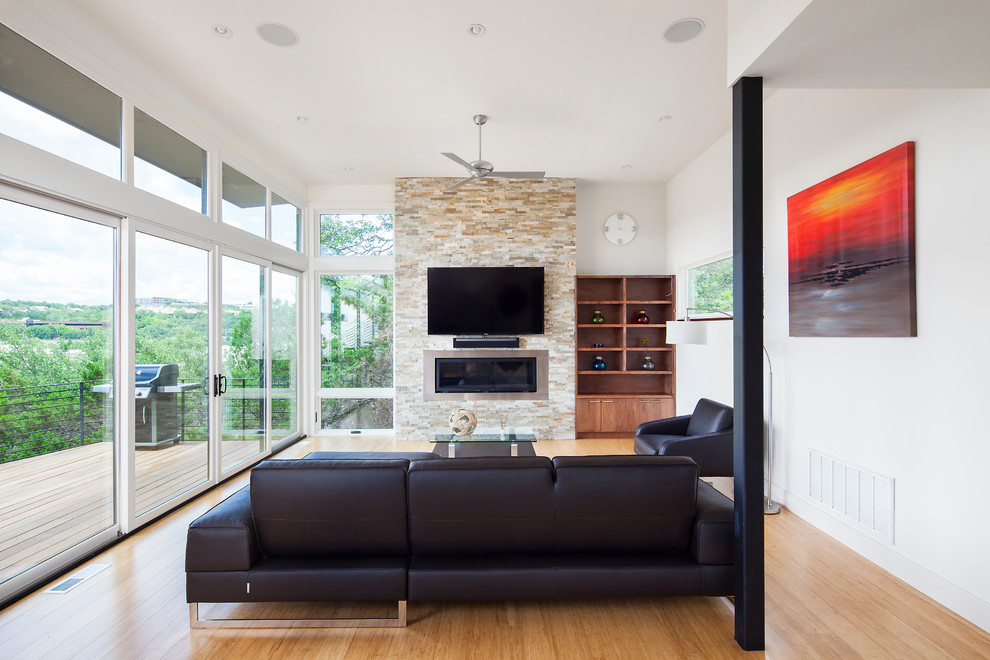 Imagen de salón para visitas abierto contemporáneo con chimenea lineal, marco de chimenea de metal y televisor colgado en la pared