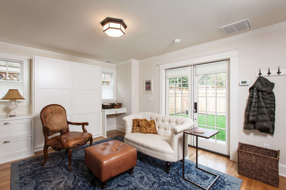 Modelo de salón para visitas abierto de estilo americano pequeño con paredes blancas, suelo de madera en tonos medios y televisor colgado en la pared
