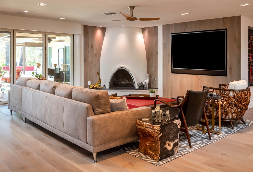 Offenes Modernes Wohnzimmer mit weißer Wandfarbe, braunem Holzboden, Eckkamin, verputzter Kaminumrandung, Multimediawand und braunem Boden in Phoenix