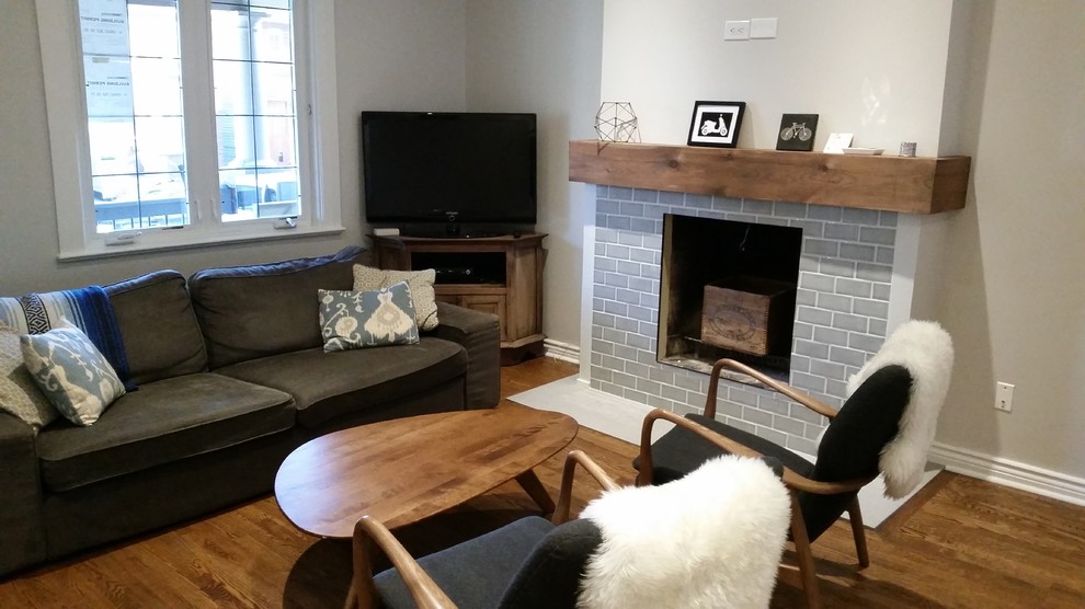 Kleines, Offenes Klassisches Wohnzimmer mit grauer Wandfarbe, dunklem Holzboden, Kamin, gefliester Kaminumrandung, freistehendem TV und braunem Boden in Toronto