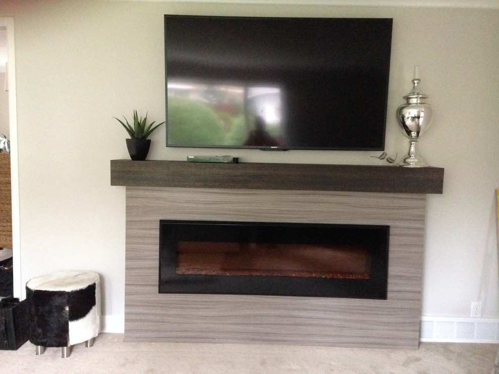 Esempio di un grande soggiorno minimal chiuso con pareti grigie, moquette, camino classico, cornice del camino in legno e TV a parete