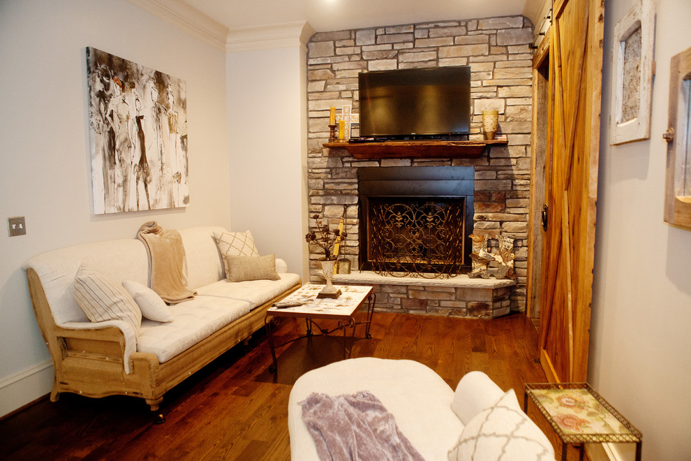 Example of a small transitional enclosed medium tone wood floor living room design in Atlanta with white walls, a standard fireplace, a stone fireplace and a wall-mounted tv