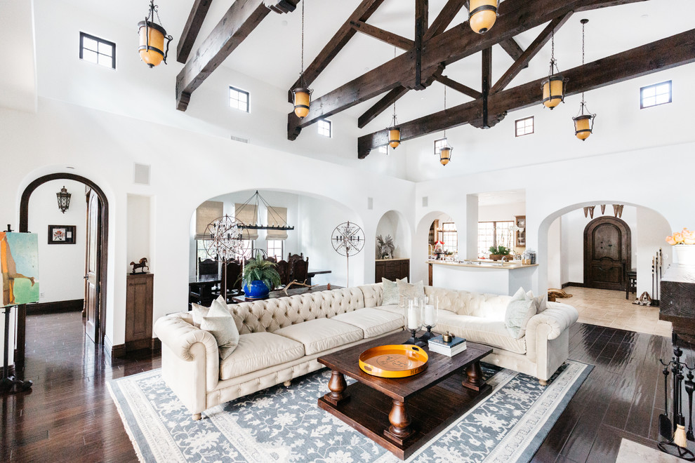 Großes, Offenes Mediterranes Wohnzimmer mit Hausbar, weißer Wandfarbe, dunklem Holzboden, Kamin und braunem Boden in Los Angeles
