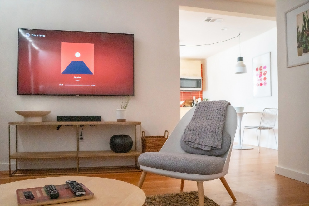 サクラメントにあるお手頃価格のミッドセンチュリースタイルのおしゃれな独立型リビング (無垢フローリング、壁掛け型テレビ、オレンジの床) の写真