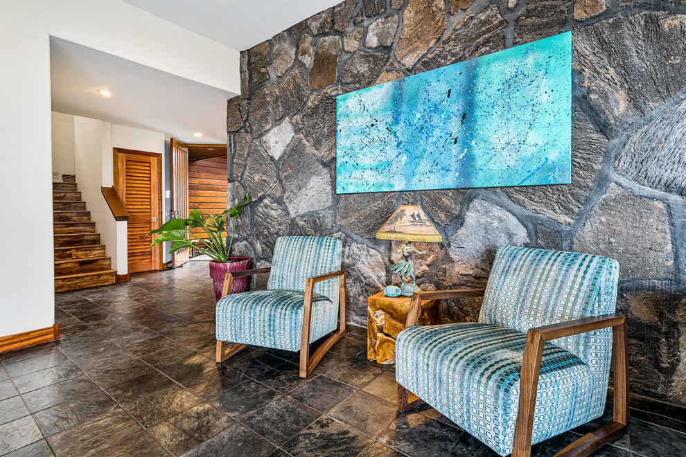 ハワイにある広いトロピカルスタイルのおしゃれなLDK (白い壁、スレートの床、壁掛け型テレビ、黒い床) の写真