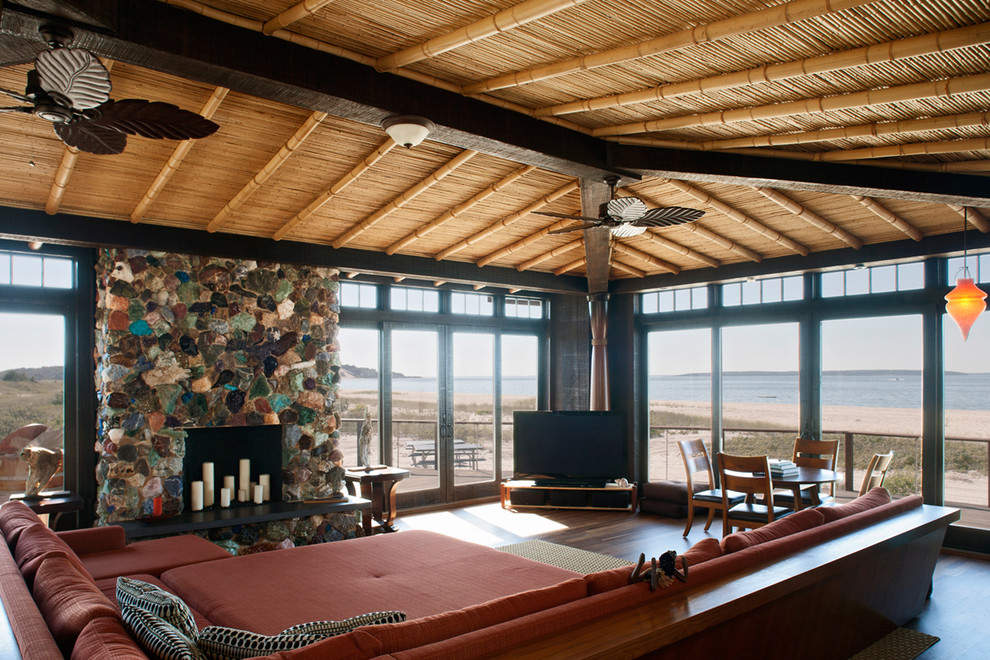 Exempel på ett exotiskt vardagsrum, med en standard öppen spis, en spiselkrans i sten och en fristående TV