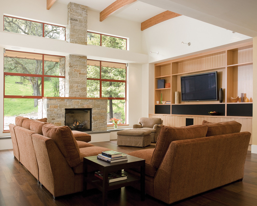 На фото: гостиная комната в стиле модернизм с фасадом камина из камня с