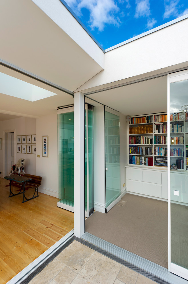 Idée de décoration pour un salon design ouvert avec une bibliothèque ou un coin lecture, un mur blanc et un sol en bois brun.