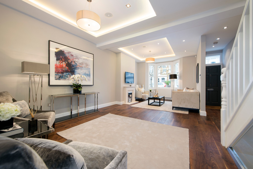 This is an example of a large contemporary open plan living room in London with grey walls, dark hardwood flooring, a standard fireplace, a stone fireplace surround and a wall mounted tv.