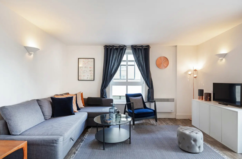 На фото: гостиная комната в современном стиле с белыми стенами, темным паркетным полом, отдельно стоящим телевизором и коричневым полом с