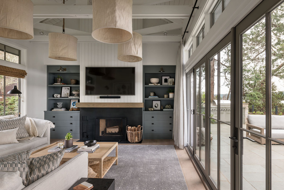Landhaus Wohnzimmer mit weißer Wandfarbe, hellem Holzboden, Kamin, TV-Wand, braunem Boden, Kaminumrandung aus Metall und Holzdielenwänden in Seattle