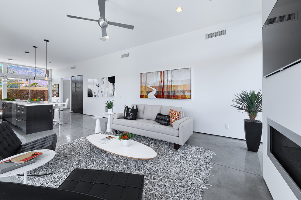 Offenes Retro Wohnzimmer mit weißer Wandfarbe, Betonboden, Gaskamin, Kaminumrandung aus Metall und TV-Wand in Sonstige