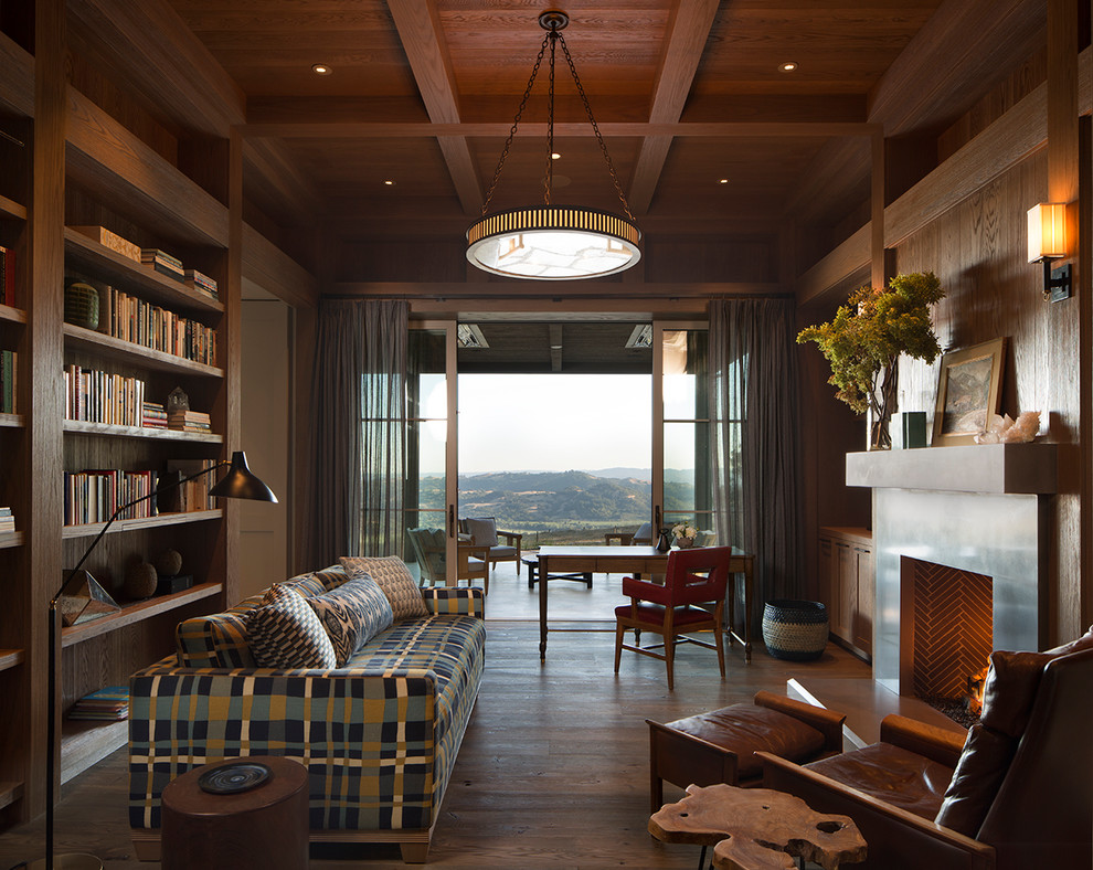 Cette image montre un salon rustique avec une bibliothèque ou un coin lecture, un mur marron, un sol en bois brun, une cheminée standard et un sol marron.
