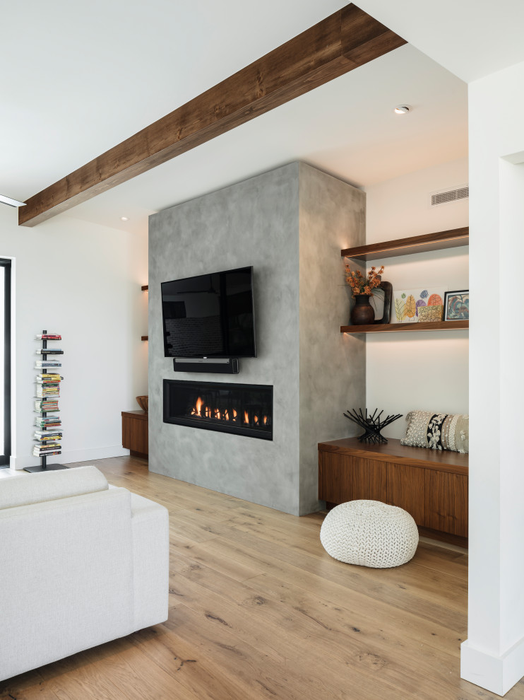 Modelo de salón abierto retro con paredes blancas, suelo de madera en tonos medios, chimenea lineal, marco de chimenea de yeso, televisor colgado en la pared y vigas vistas