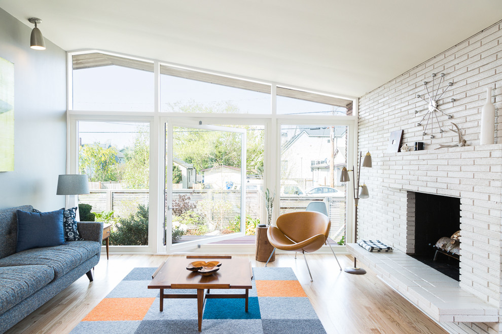 Inspiration for a midcentury living room in Seattle with light hardwood flooring and a standard fireplace.