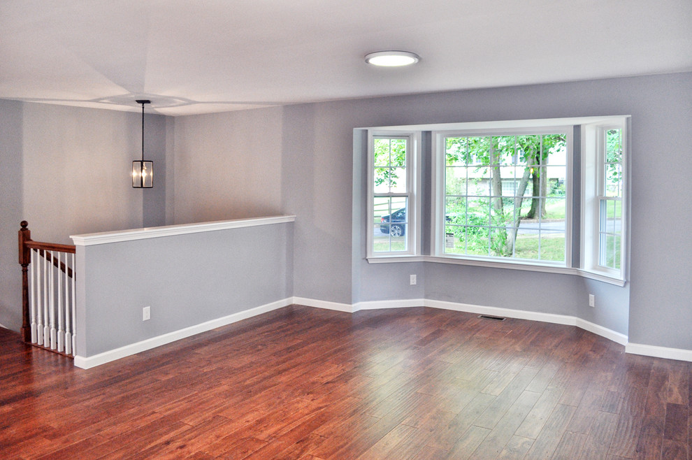 На фото: открытая гостиная комната среднего размера в стиле неоклассика (современная классика) с серыми стенами и светлым паркетным полом без камина с