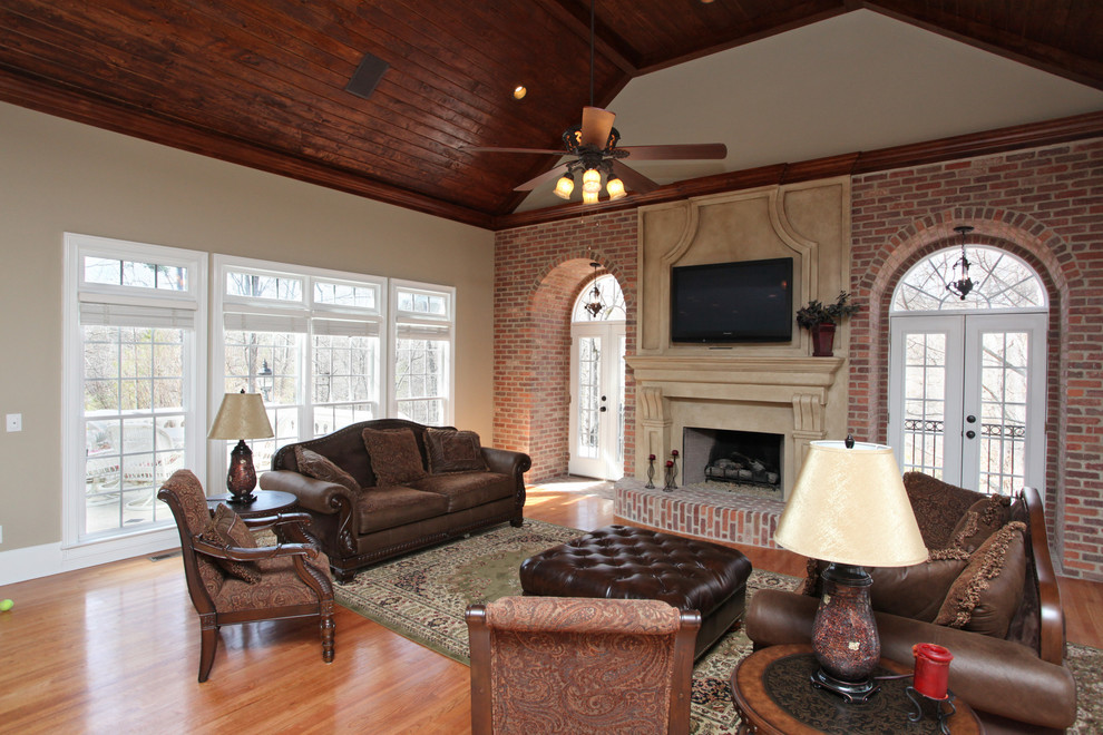 Cette image montre un grand salon traditionnel ouvert avec une salle de réception, un mur blanc, un sol en bois brun, une cheminée standard, un téléviseur fixé au mur et éclairage.