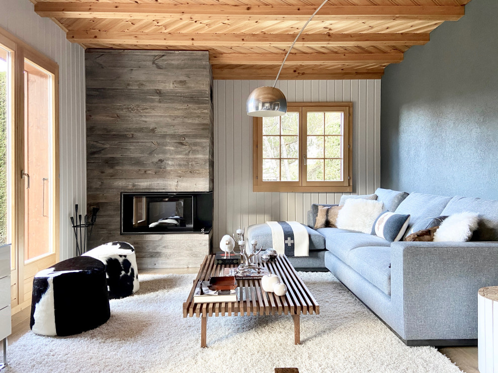 Пример оригинального дизайна: гостиная комната в стиле рустика с угловым камином и фасадом камина из дерева