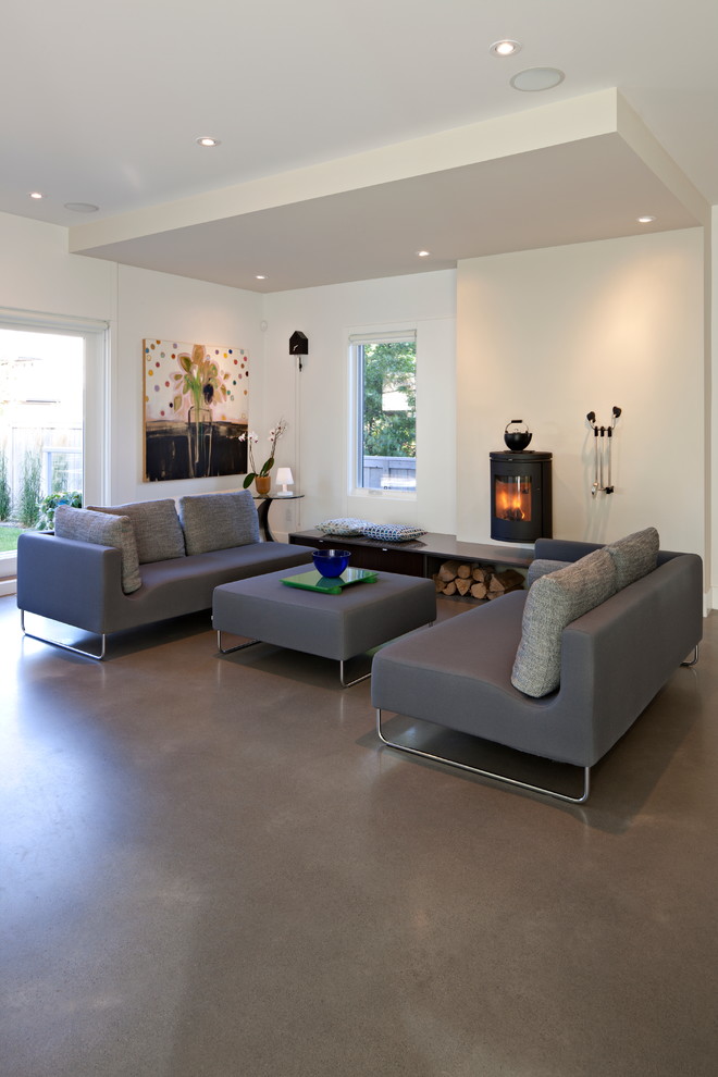 Стильный дизайн: открытая гостиная комната среднего размера в современном стиле с разноцветными стенами, бетонным полом, печью-буржуйкой, фасадом камина из металла и серым полом без телевизора - последний тренд
