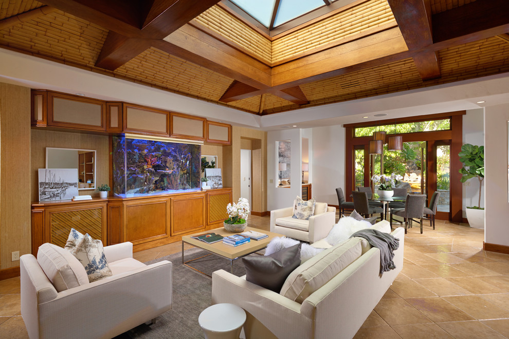 This is an example of a world-inspired open plan living room in Orange County with no fireplace and beige floors.