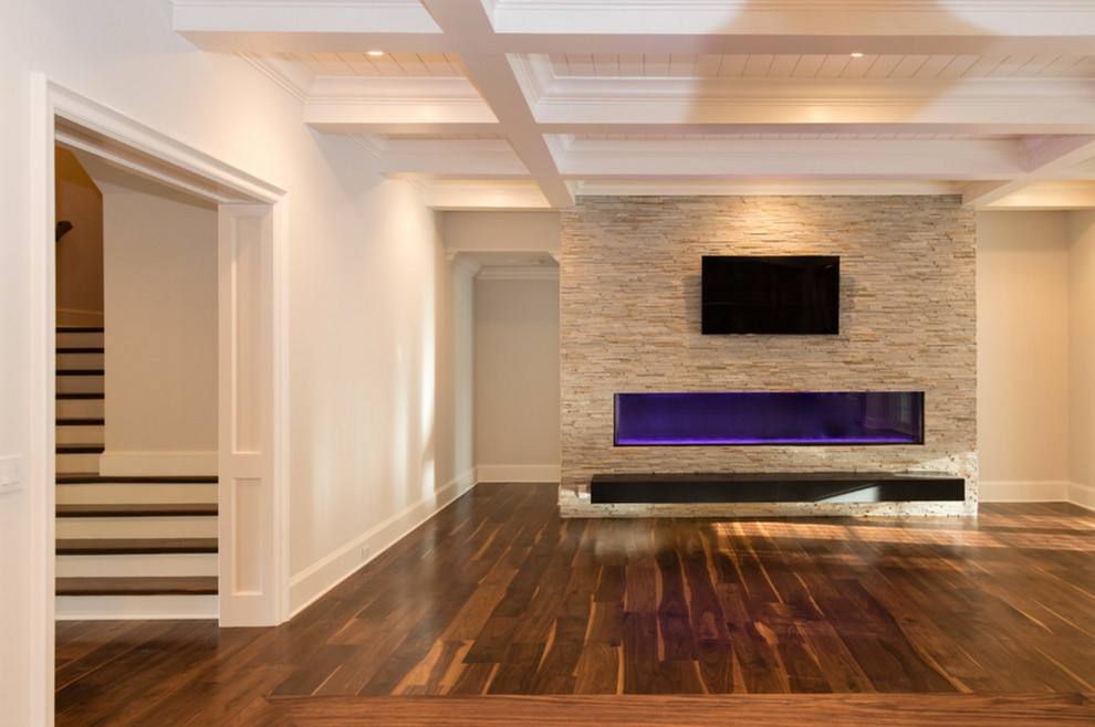 Imagen de salón abierto clásico renovado grande con paredes beige, suelo de madera en tonos medios, chimenea lineal, marco de chimenea de piedra y televisor colgado en la pared