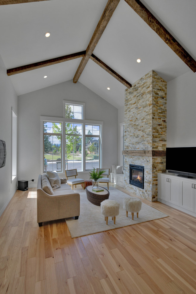 Großes, Offenes Landhausstil Wohnzimmer mit weißer Wandfarbe, hellem Holzboden, Kamin, Kaminumrandung aus Stein, TV-Wand und beigem Boden in Portland