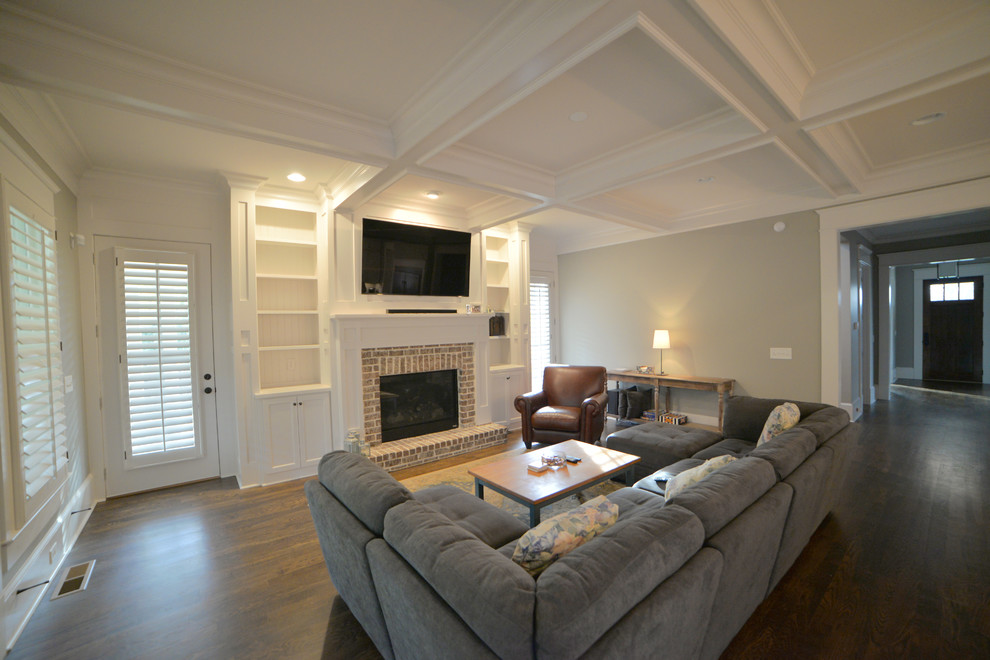 Großes, Offenes Klassisches Wohnzimmer mit grauer Wandfarbe, dunklem Holzboden, Kamin, Kaminumrandung aus Backstein und TV-Wand in Atlanta