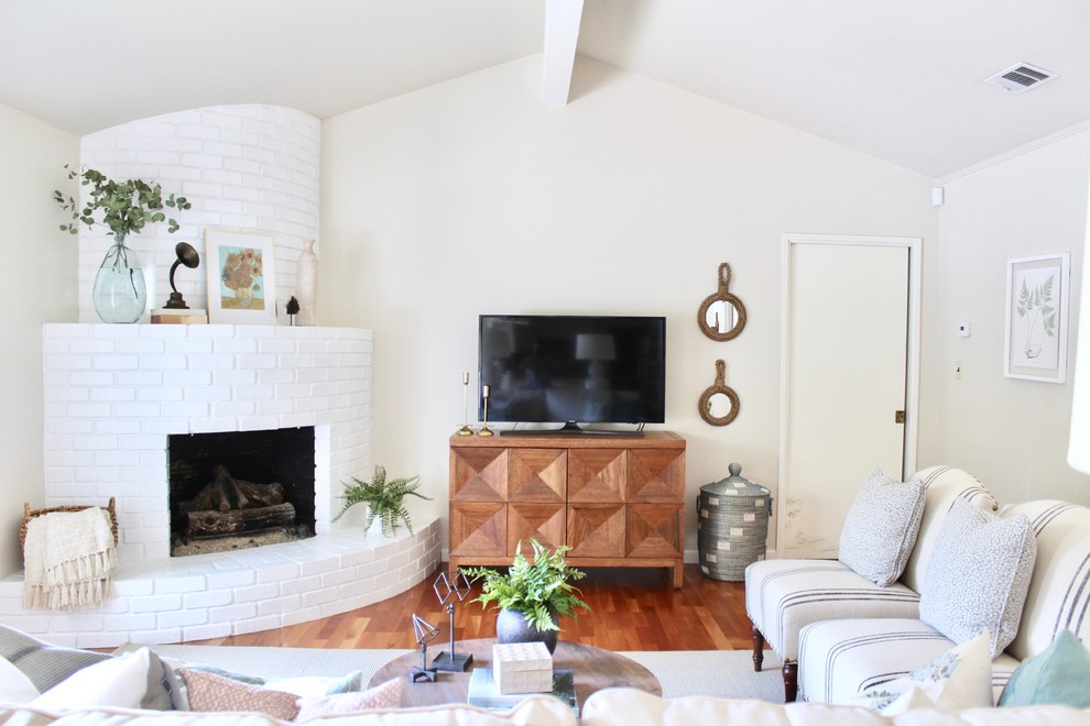 Repräsentatives Country Wohnzimmer mit beiger Wandfarbe, braunem Holzboden, Eckkamin, Kaminumrandung aus Backstein, freistehendem TV und braunem Boden in Sacramento
